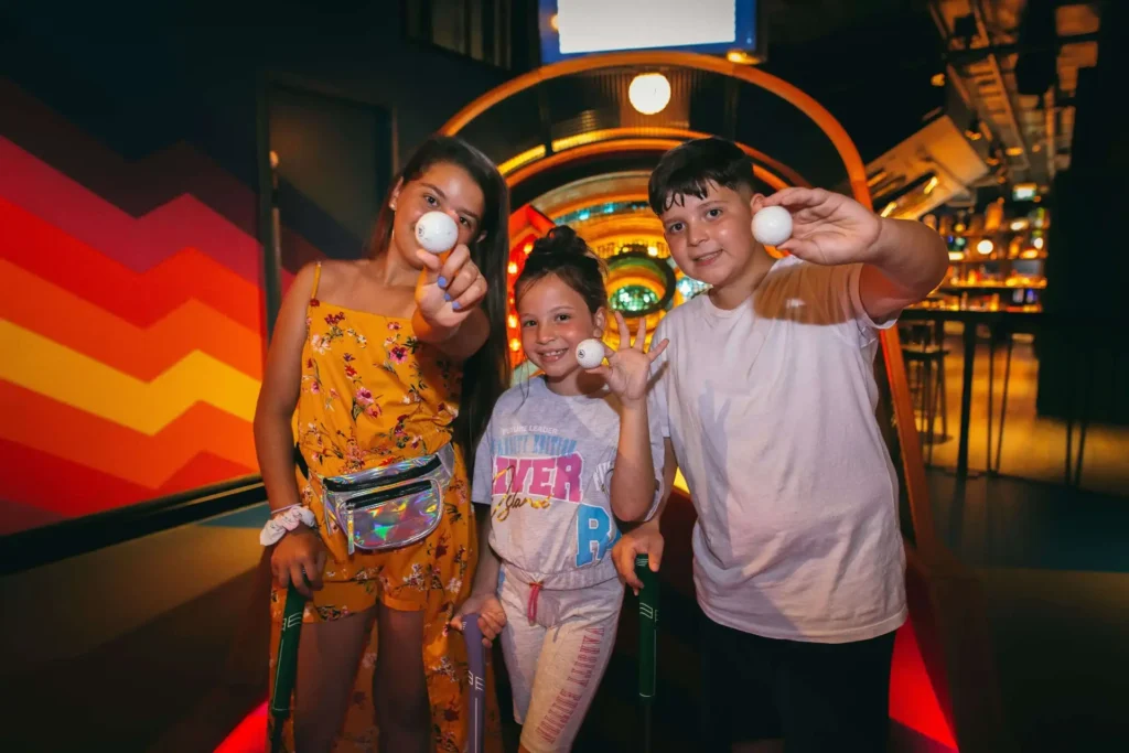 Kids holding up a golf ball at Puttshack