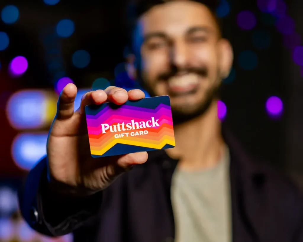 Man holding up a Puttshack giftcard